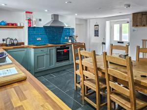 eine Küche mit blauen Schränken sowie einem Tisch und Stühlen in der Unterkunft Ivy Cottage - Tq4 in Boscastle