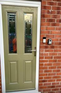 a green door on a brick building with a brick wall at Cosy Corner Cheadle in Cheadle +8 photos