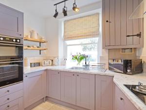 eine Küche mit weißen Schränken und einem Fenster in der Unterkunft Duck Cottage in Gargrave