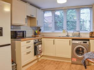 een keuken met witte kasten en een wasmachine bij South Wing Coldharbour Park Farm in Rake