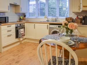 een keuken met een tafel met daarop een vaas met bloemen bij South Wing Coldharbour Park Farm in Rake