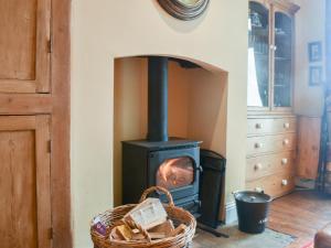 a wood stove in a room with a basket at Lancashire And Yorkshire Cottage in Hellifield