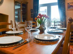 a wooden table with plates and wine glasses on it at Lancashire And Yorkshire Cottage in Hellifield