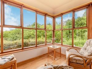 een kamer met grote ramen en een tafel en stoelen bij Cwmfron House in Llanidloes