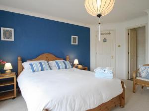 a bedroom with a large bed with a blue wall at Spinnakers in Falmouth +6 photos