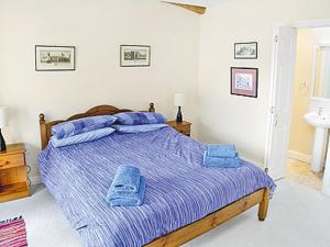 a bedroom with a bed with blue blankets and a sink at Aira Cottage in Watermillock