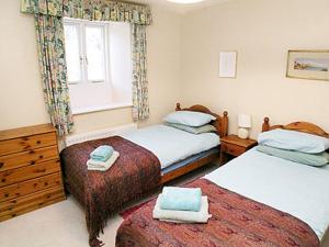 a bedroom with two beds and a window at Aira Cottage in Watermillock +2 photos