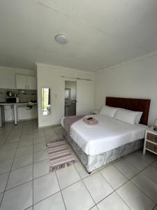 a bedroom with a large white bed and a kitchen at Riverview Pool Resort and Lodge in Moletlane