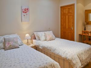 a bedroom with two beds and a wooden door at Willow Cottage - E4778 in Atwick +2 photos