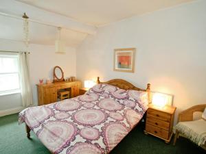 ein Schlafzimmer mit einem Bett mit einer rosa Tagesdecke in der Unterkunft Drum And Monkey Cottage in Chapel en le Frith