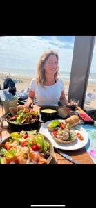 a woman sitting at a table with plates of food at Luxus Chalet Wattenmeerblick in Westerland