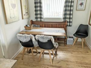 uma sala de jantar com uma mesa de madeira e 2 cadeiras em Beach Cottage em Gairloch