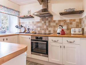 a kitchen with white cabinets and a stove top oven at Lodge Farm Cottage in Haworth +13 photos