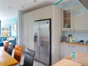 a kitchen with a stainless steel refrigerator and a table at Llywnfor in Morfa Nefyn