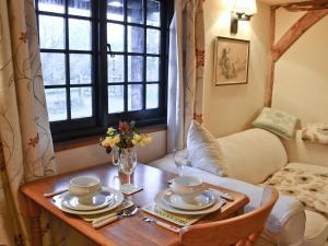 a room with a table with plates and flowers on it at Byre Cottage - 29410 in Elmsted