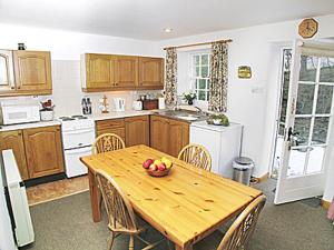 a kitchen with a wooden table with a bowl of fruit on it at 2 Farfield Cottages in Sedbergh