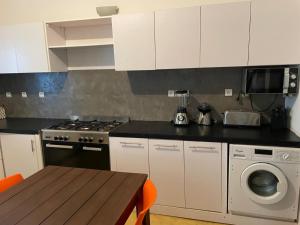a kitchen with white cabinets and a table and a stove at Lou Fatm' Popenguine in Poponguine