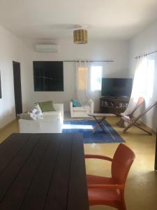 a living room with a white couch and a tv at Lou Fatm' Popenguine in Poponguine