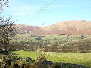 a view of a field with a hill in the background at 2 Farfield Cottages in Sedbergh