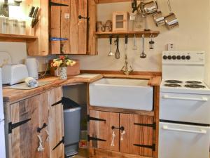 a kitchen with wooden cabinets and a white sink at Byre Cottage - 29410 in Elmsted