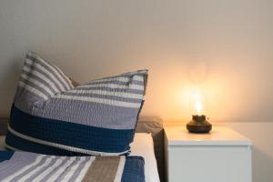 a bed with a pillow and a candle on a table at Inselglück App 4 in Norderney +8 photos