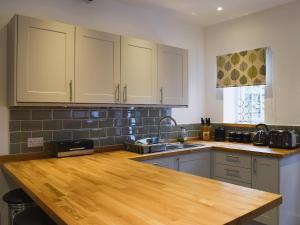 a kitchen with white cabinets and a wooden counter top at Acorn Lodge Cottage in Keswick
