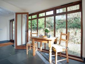 einen Tisch und zwei Stühle in einem Zimmer mit Fenstern in der Unterkunft Uk45541-Old Stable Cottage in Sticklepath + 35 Fotos