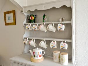 a cupboard filled with lots of tea cups at Shore Cottage in Carsluith