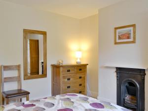 a bedroom with a bed and a dresser and a fireplace at 14 Greta Villas in Keswick +2 photos