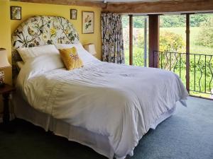 Un dormitorio con una cama grande con sábanas blancas y un balcón en Oldfield, en Warminster