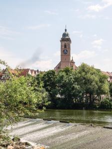 ein Gebäude mit einem Uhrturm neben einem Fluss in der Unterkunft Belsers Hotel in Nürtingen