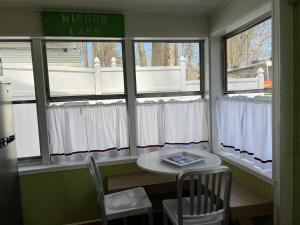 a table and chairs in a room with windows at Cottage 12 - King Bed Child Loft w Twin Private Bath Kitchenette Pets Allowed Fee applies in Wolfeboro