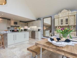 une cuisine avec des placards blancs et une table avec un vase de fleurs dans l'établissement Lily Pad Lodge, à Donington on Bain