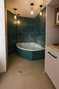a bathroom with a tub with green walls and lights at קציר ריזורט in Migdal