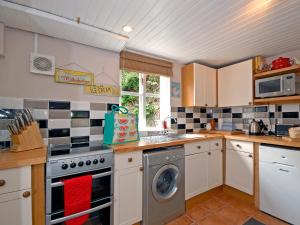 eine Küche mit einem Herd und einer Waschmaschine in der Unterkunft Crows Cottage in Fishguard
