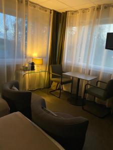 a room with a table and chairs and a table and windows at Résidence Cosyade équipée d'un parking privé gratuit in Bourbourg