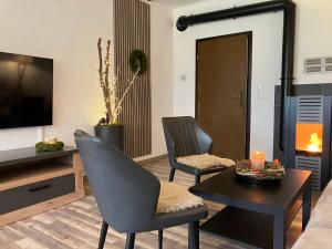 een woonkamer met 2 stoelen, een tafel en een tv bij Landhaus Augenblicke in Olsberg - modernes Ferienhaus mit Garten in Olsberg