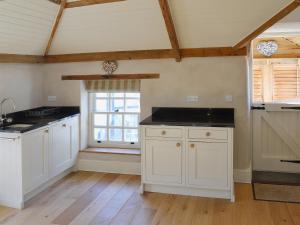 a kitchen with white cabinets and a window at The Stables By The Sea in Newquay +11 photos