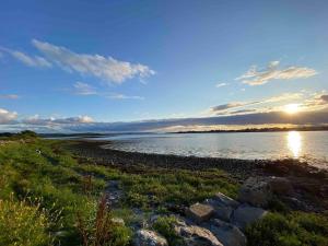 una puesta de sol sobre un cuerpo de agua con rocas en Cuileann, en Clarinbridge 10 fotos más