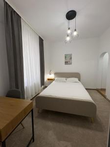 a white bedroom with a bed and a table at Vila Ada in Bucharest