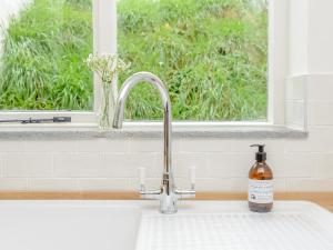 ein Waschbecken in einer Küche mit Fenster in der Unterkunft Eton Cottage in Farnham