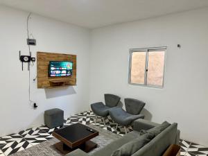 a living room with a couch and chairs and a tv at Casa no centro na Praia do Preá/CE in Prea