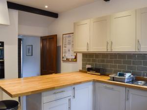 a kitchen with white cabinets and a wooden counter top at Acorn Lodge Cottage in Keswick