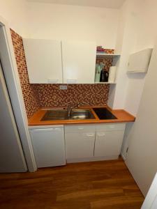 une petite cuisine avec des armoires blanches et un évier dans l'établissement CityStay Dortmund, à Dortmund