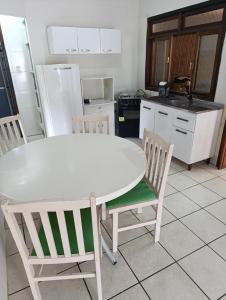 a kitchen with a white table and two chairs at Casa em Itapema in Itapema +2 photos