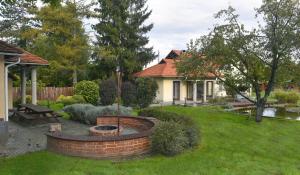 a garden with a fire pit and a house at Erdőparty Vendégház in Tápiószecső