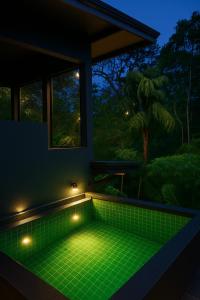 een groene jacuzzi in een kamer met een raam bij Rainforest cabin in Deniyaya