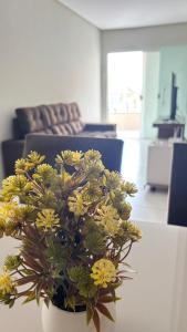 un vase avec des fleurs jaunes sur une table dans un salon dans l'établissement Apartamento espaçoso e localização perfeita, à Petrolina