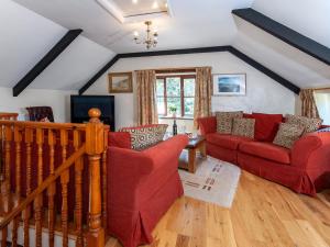 ein Wohnzimmer mit zwei roten Sofas und einem TV in der Unterkunft Carn Llidi Cottage in St. Davids