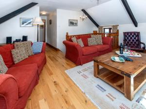ein Wohnzimmer mit roten Sofas und einem Holztisch in der Unterkunft Carn Llidi Cottage in St. Davids